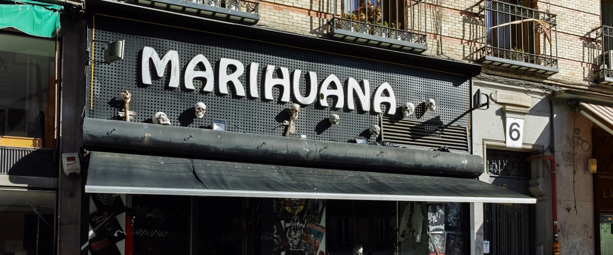 Fachada de un club social de cannabis en España con un gran cartel de marihuana sobre la entrada.