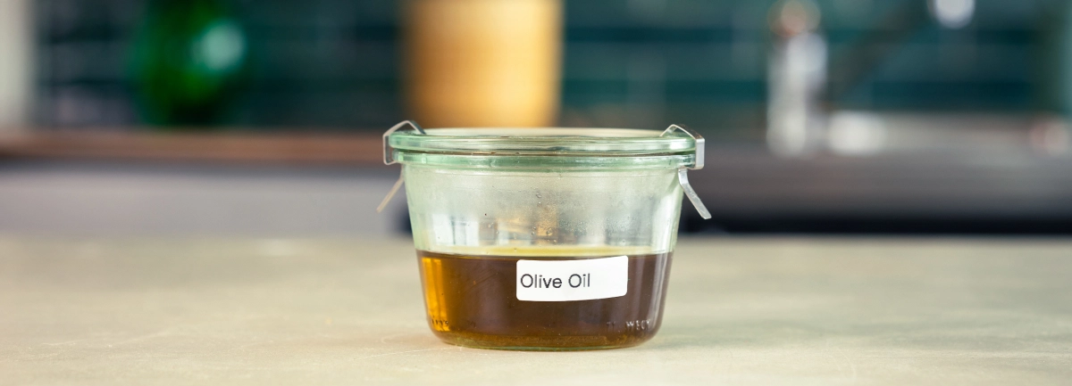 Conservación del aceite de oliva infusionado con cannabis Recipiente de cristal con aceite de oliva infusionado con cannabis, etiquetado y listo para guardar.
