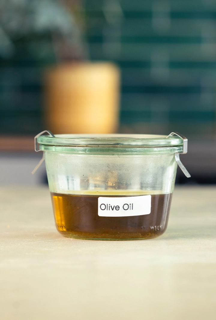 Conservación del aceite de oliva infusionado con cannabis Recipiente de cristal con aceite de oliva infusionado con cannabis, etiquetado y listo para guardar.