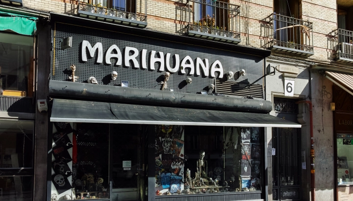 Fachada de un club social de cannabis en España con un gran cartel de marihuana sobre la entrada.