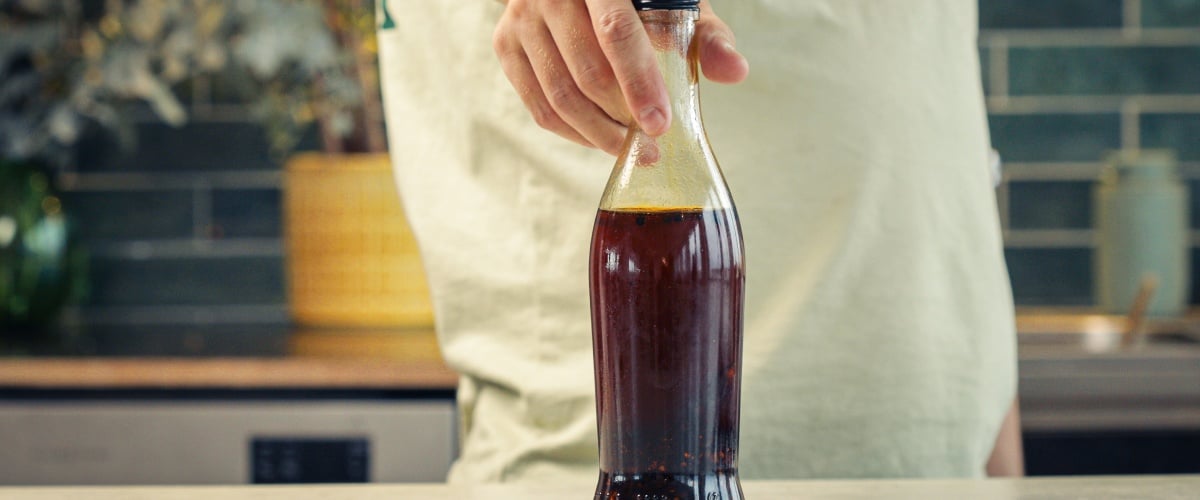 Paso 4: Conservar Correctamente el Aceite de Chile con Cannabis Botella de vidrio sellada llena de aceite de chile infusionado con cannabis almacenada en una cocina